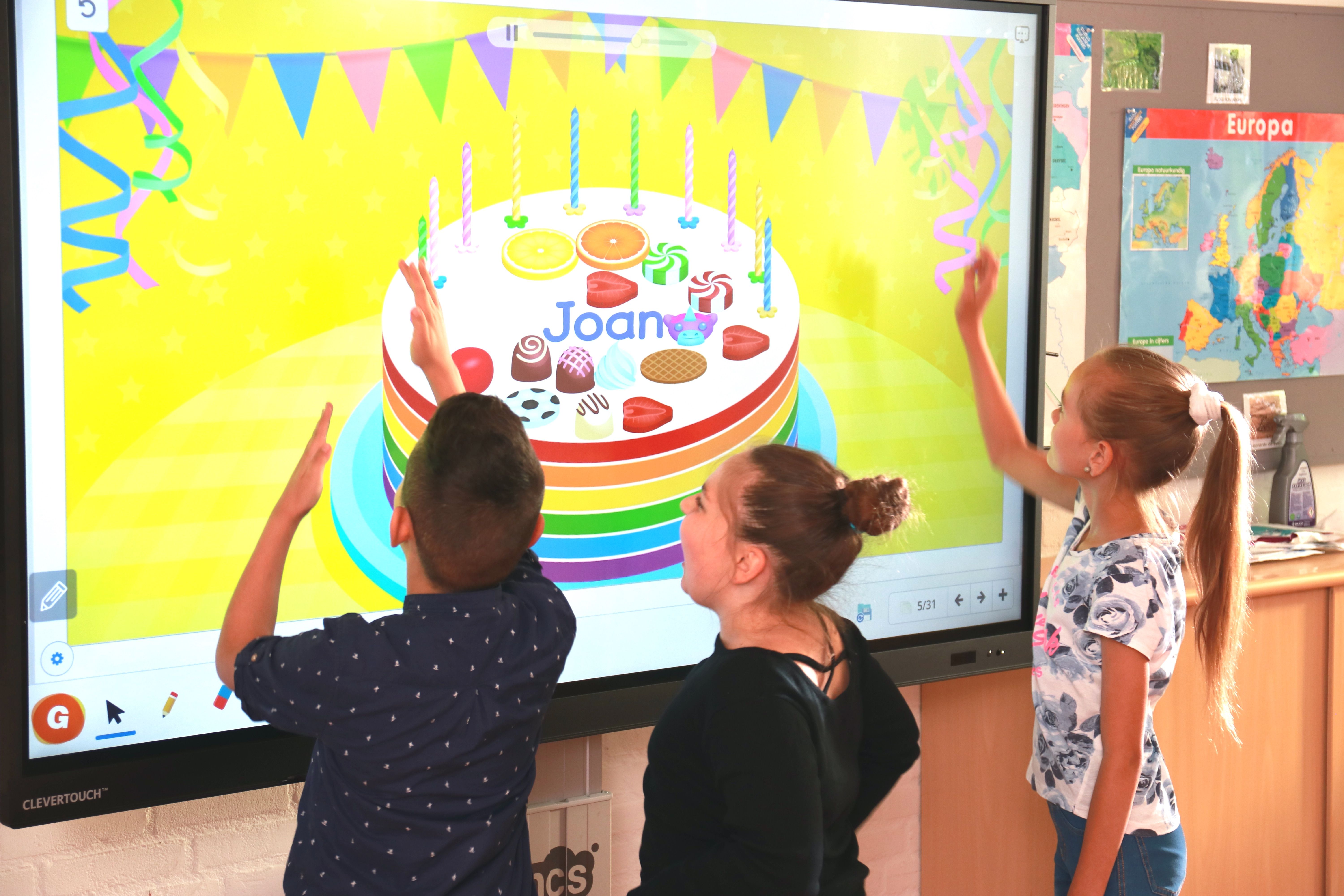 Students using a birthday cake tool on a classroom smart board